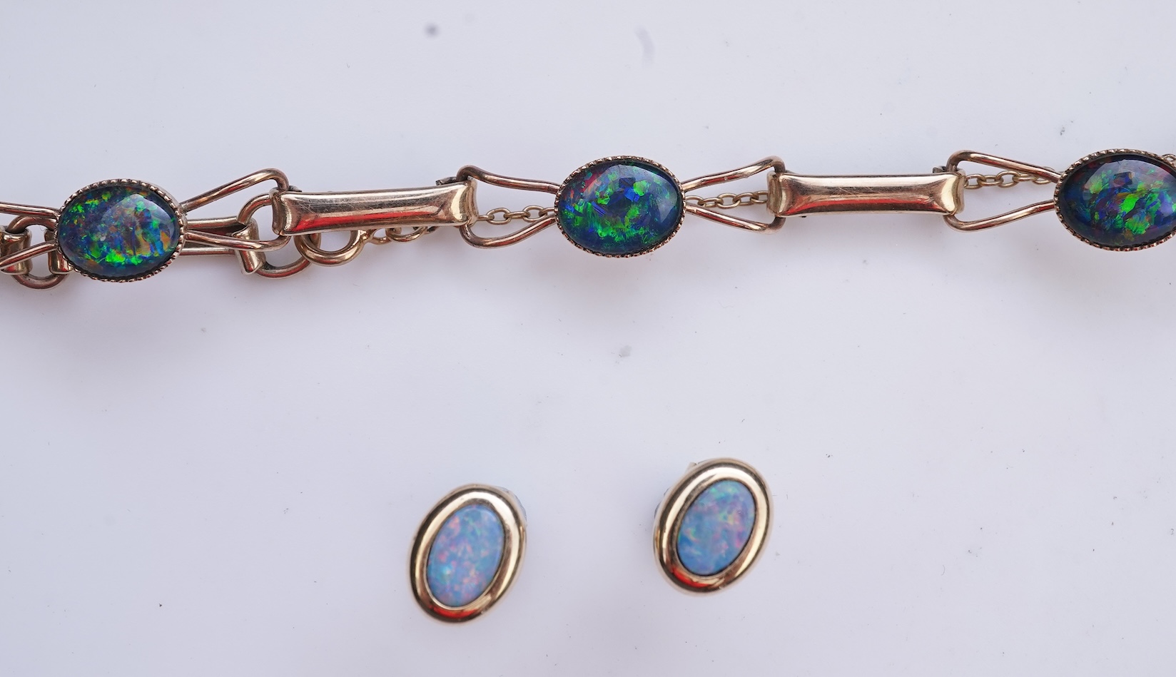 An opal triplet bracelet and pair of earrings, comprising: a gold bracelet set with opal triplets, length 18cm; and a pair of studs set with opal doublets, mounted in gold, length 0.8cm each, post fittings, stamped 585,